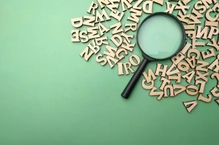 A green backdtop with a magnifying glass surrounded by letters